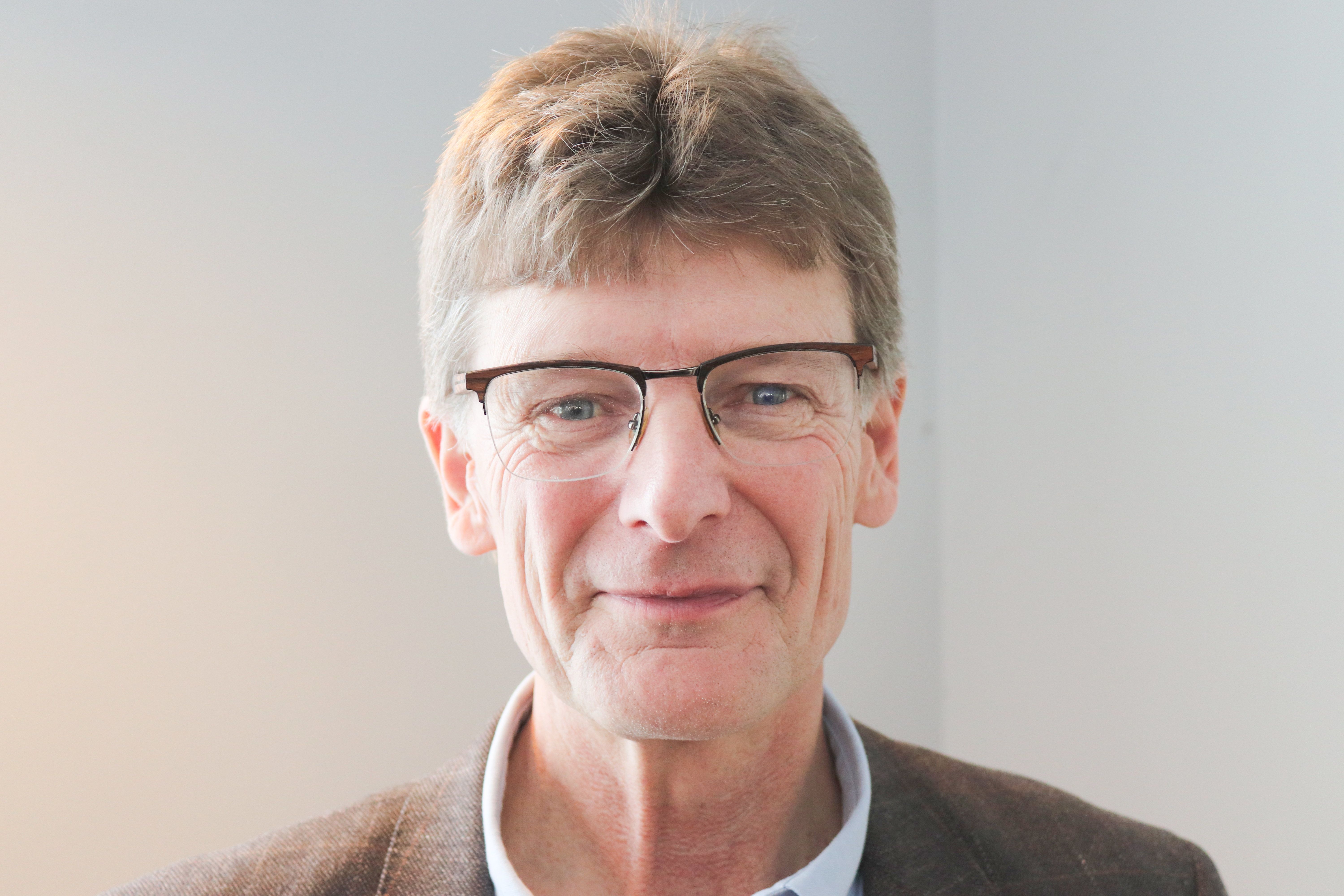 Leende medelålders man med glasögon mot ljus bakgrund