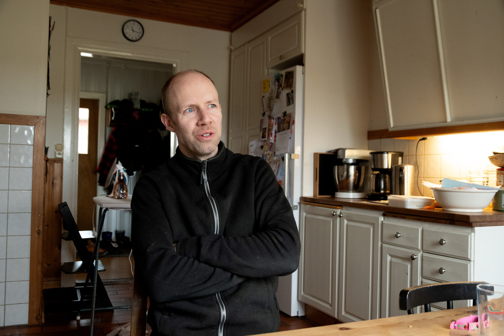 Man sitter vid köksbord med armarna i kors i ett ljust kök