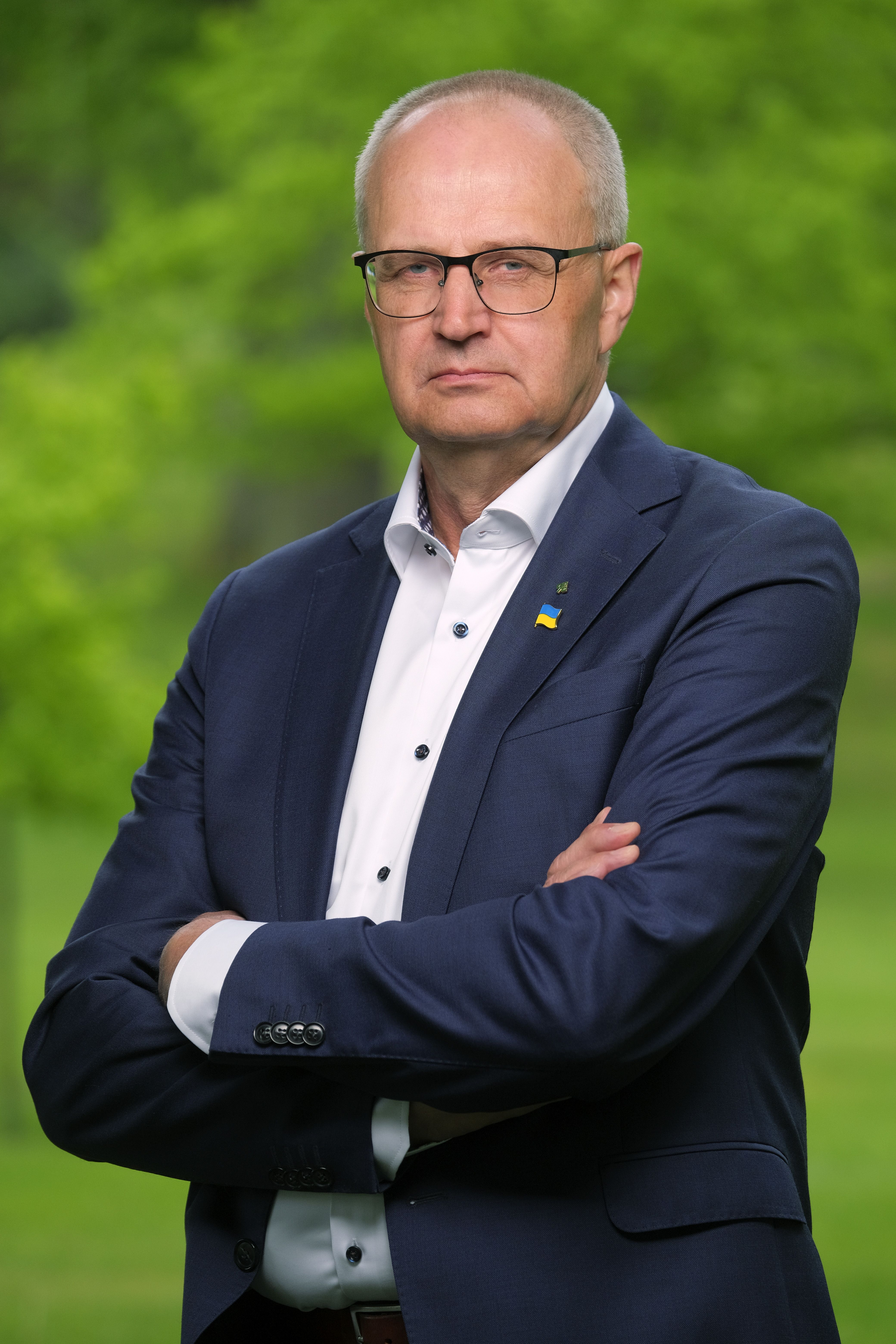 Palle Borgström står utomhus med armarna i kors mot grön bakgrund.