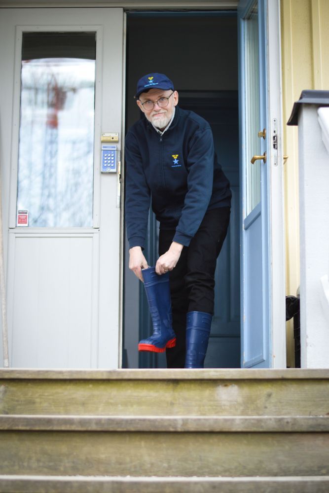 Man i dörren tar på sig blå stövlar.