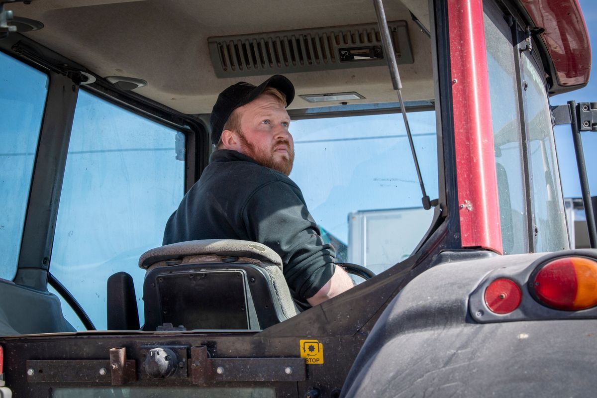 Man i keps sitter i en röd traktor och tittar bakåt i hytten