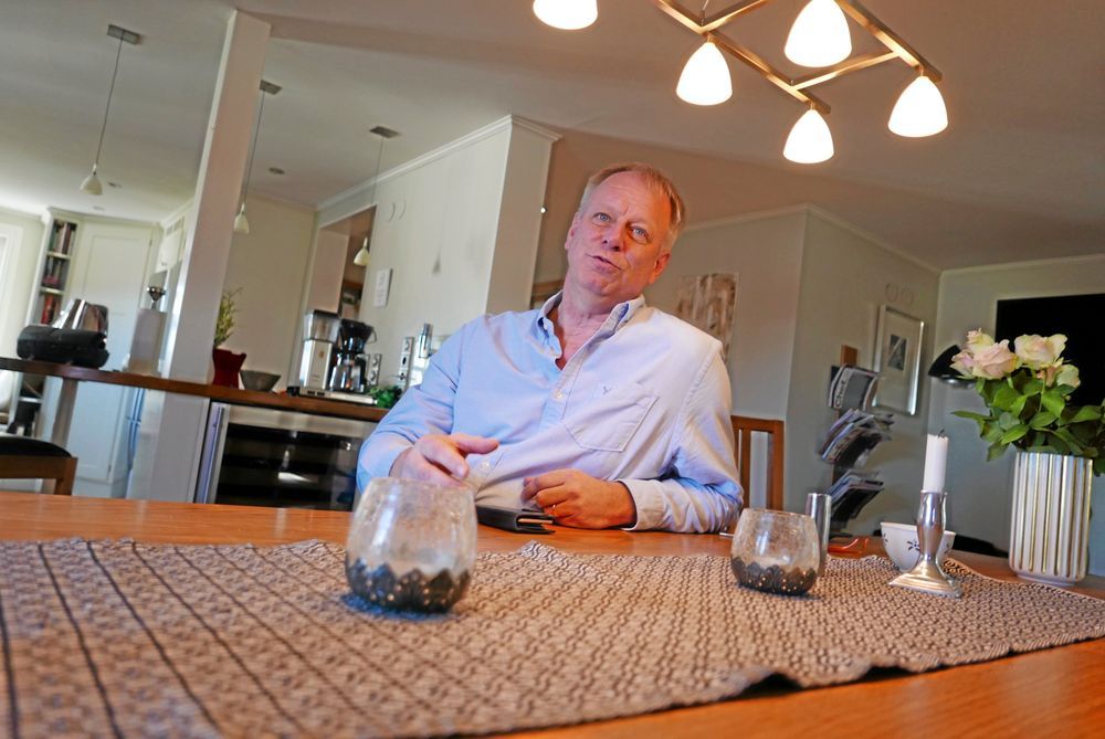 Man vid matbord i modernt kök med lampa över huvudet.