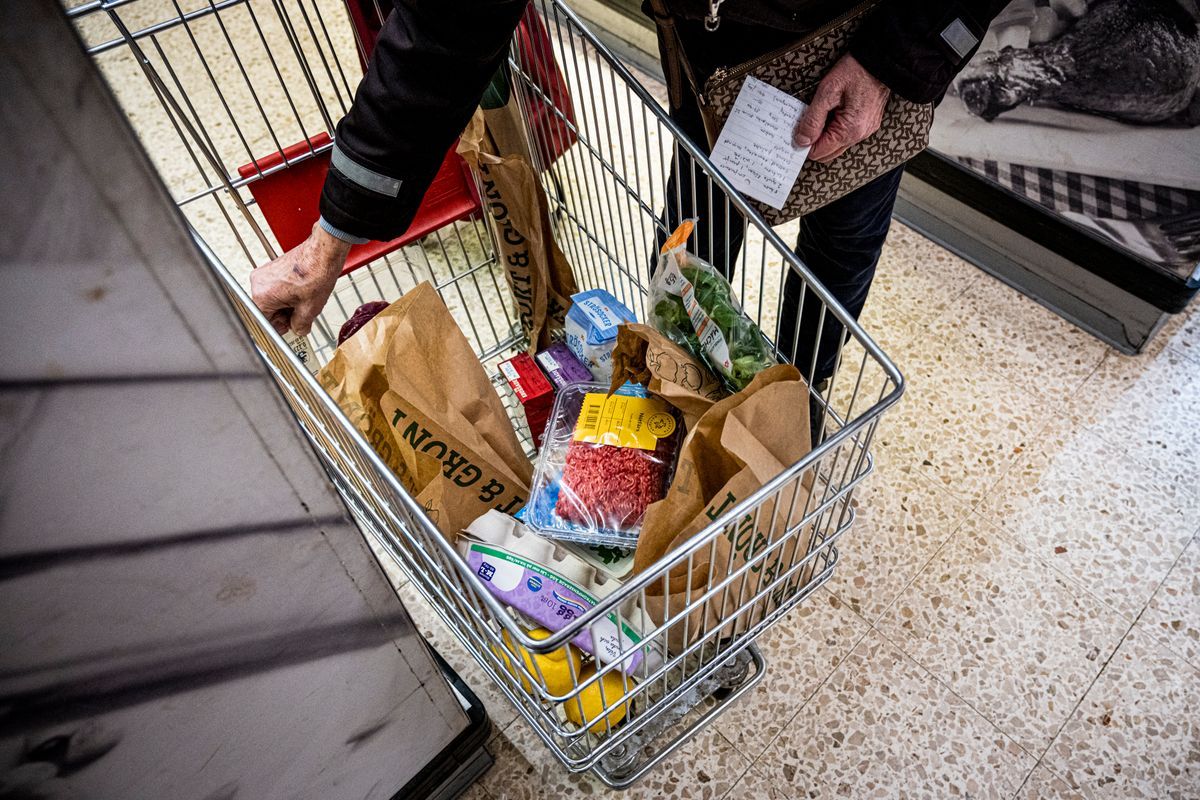 Person med handlingslista och matkorg fylld med varor i mataffär