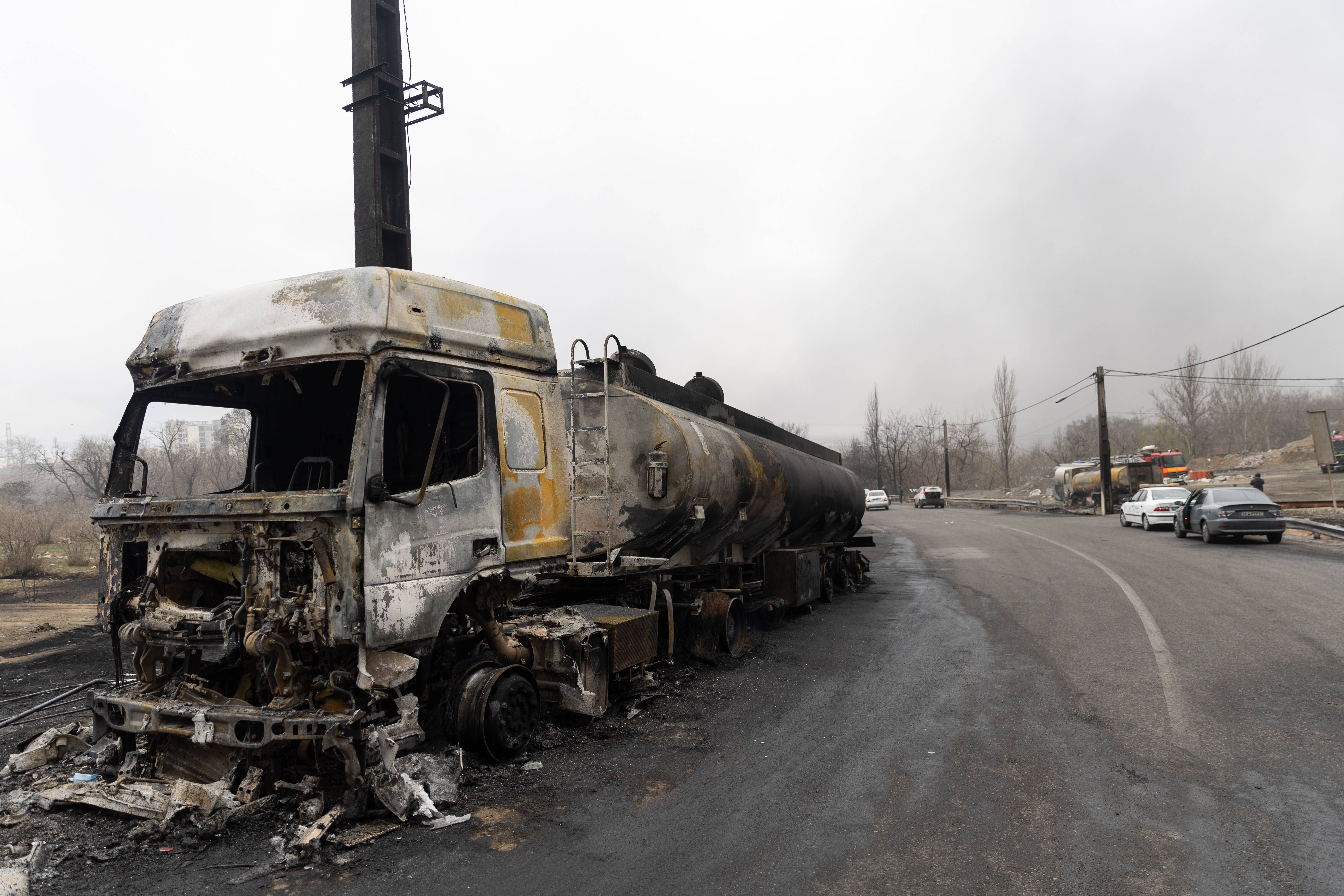 Utbränd tanklastbil vid en ödslig landsväg under grå, dimmig himmel